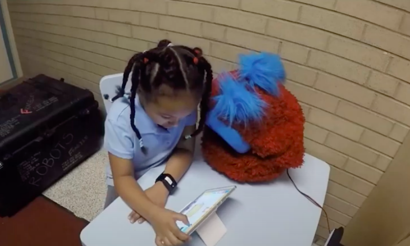 Child does homework with the help of a fluffy robot.