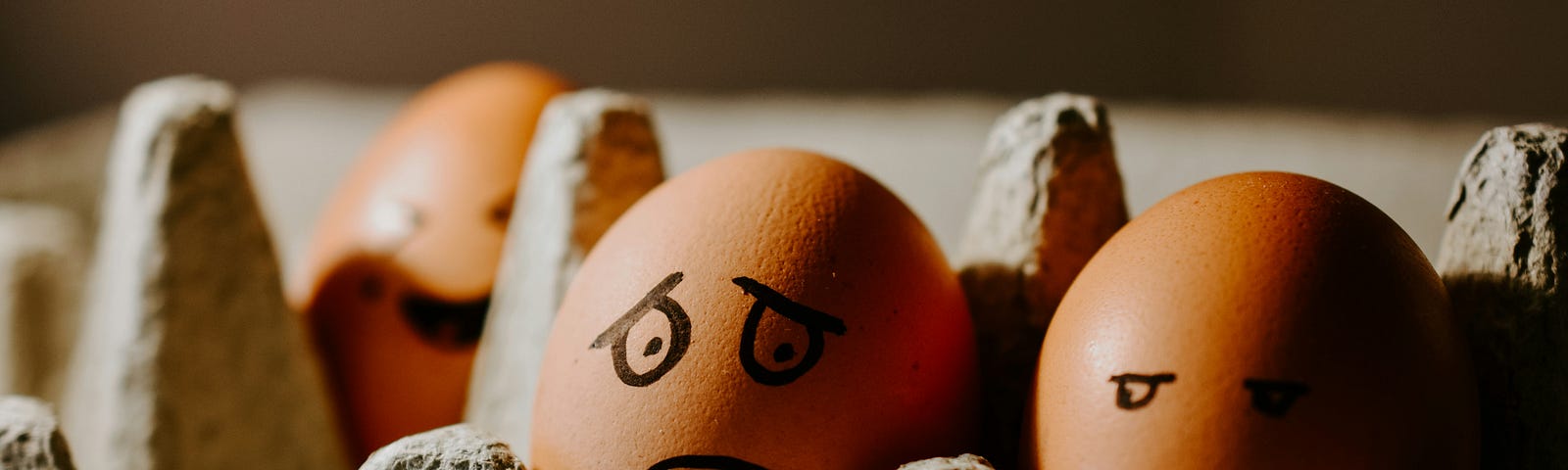 Three eggs in a carton with drawn faces displaying different emotions, representing anxiety and worry.