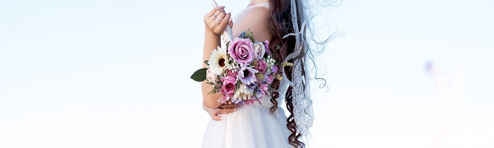 A young bride in a long white gown with a bouquet.