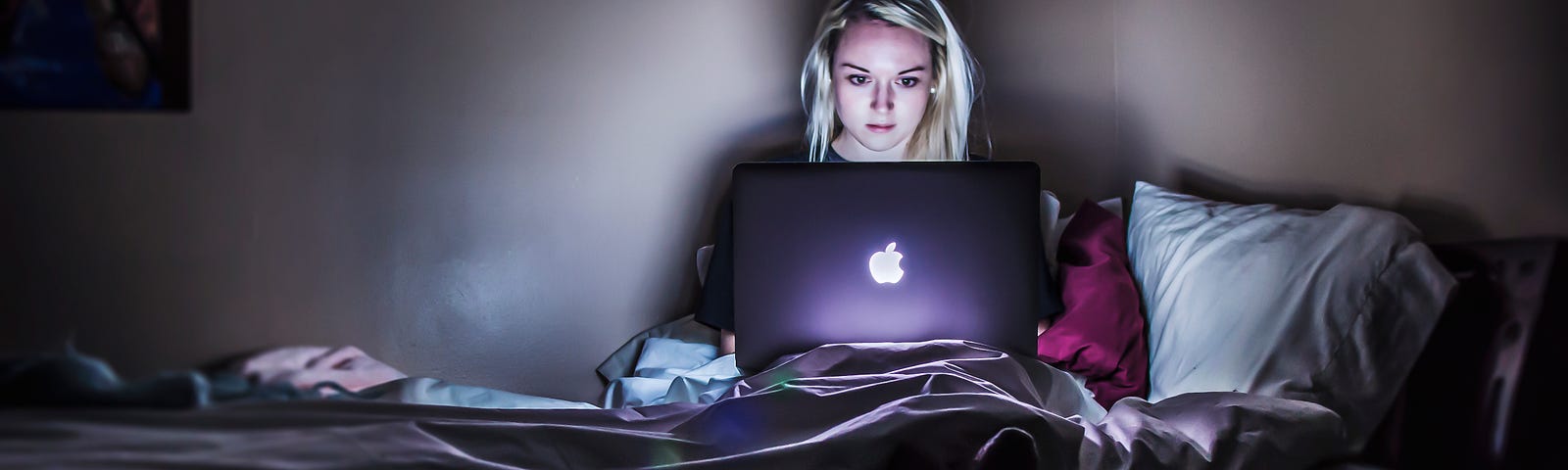 women sitting in the dark with laptop open