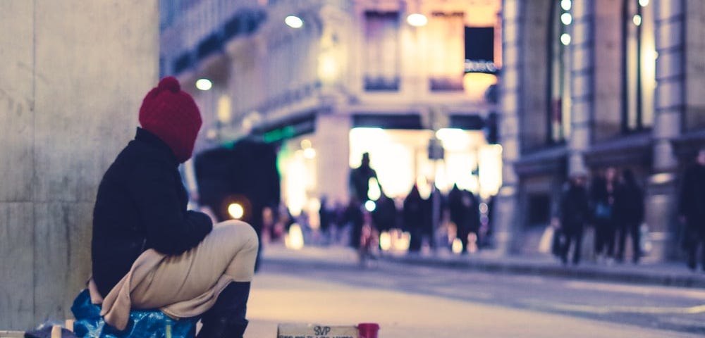 Homeless man sitting on a city corner