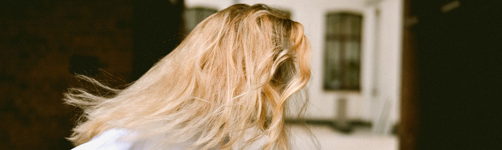 Blonde haired girl twirling away from the camera in front of an alley arch