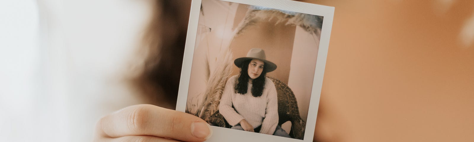 Woman holding up a polaroid of herself, her personal brand