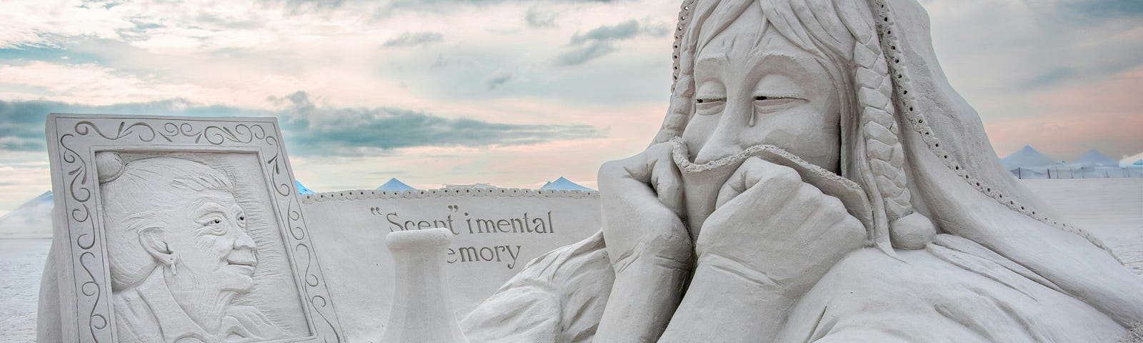 sand art of woman grieving as she looks at a photo and a bottle of unstopped perfume