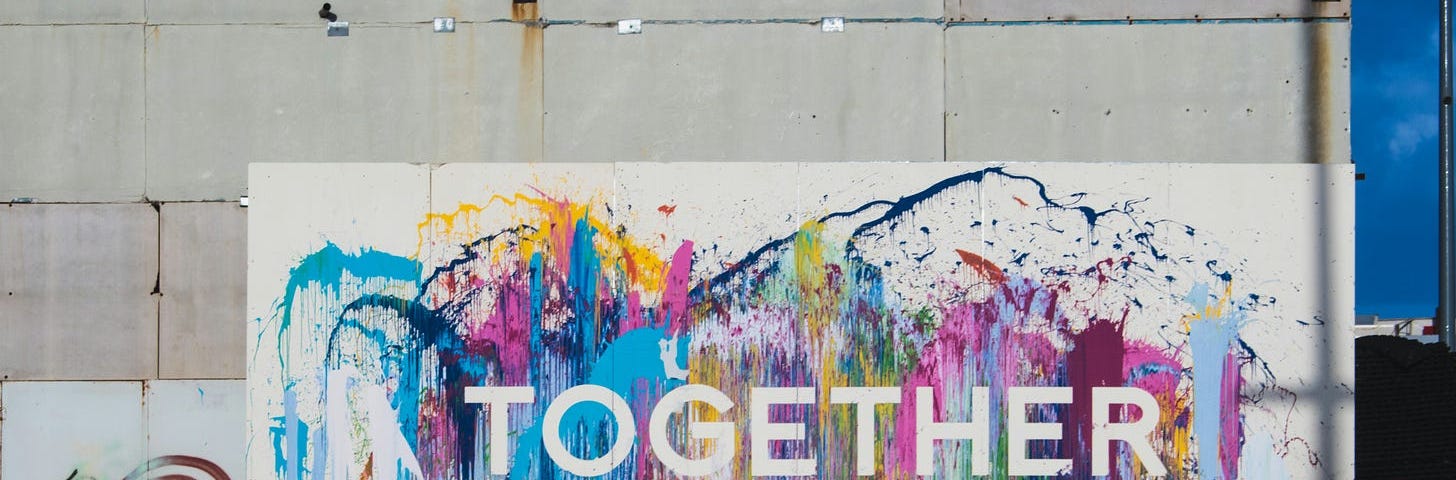 Paint-splattered sign that has “Together” printed in the middle