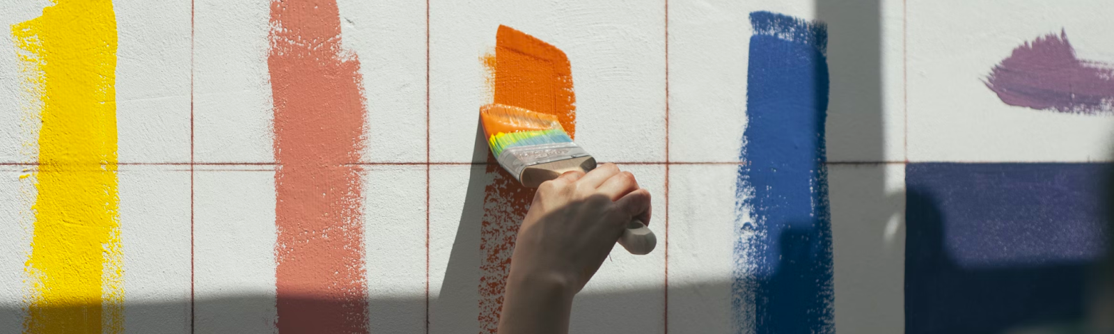 A person using a paintbrush to apply paint to a wall.