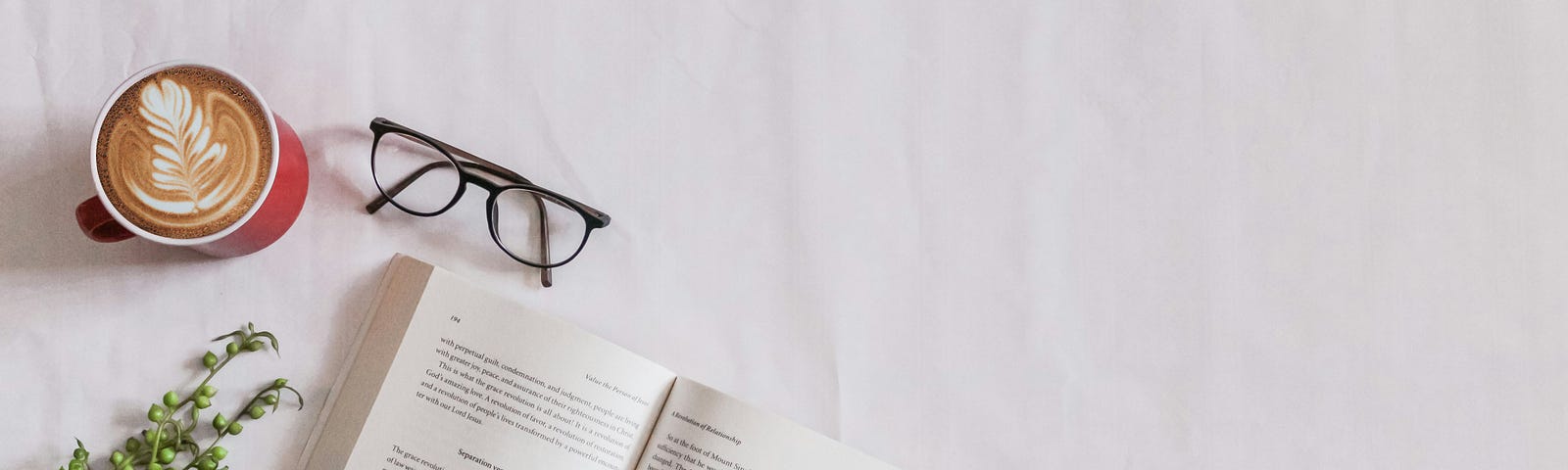 Arial view of a book, glasses, and a cup of coffee on a white background