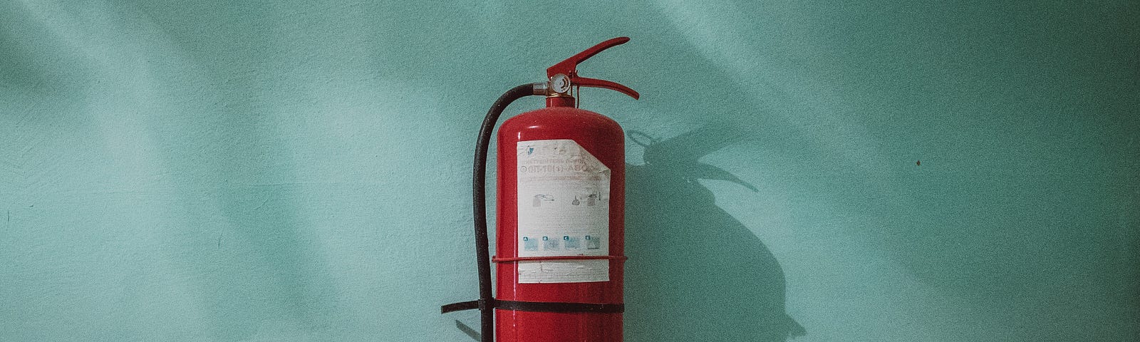 A fire-extinguisher hangs from a blue wall.
