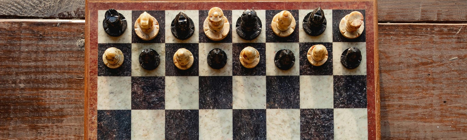 a chess board with all the pieces in play, in their starting positions, but each piece is alternating white and black on each side instead of the standard chess starting positions