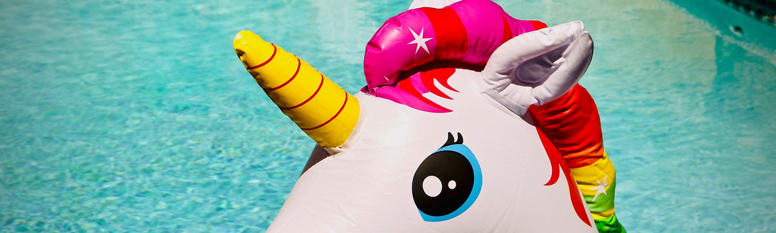 Inflatable unicorn with a rainbow mane at a pool