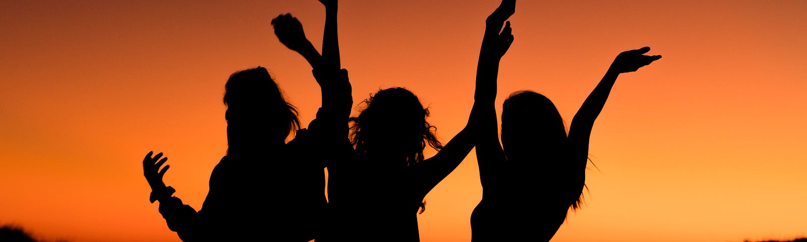 three women silhouetted against a sunset background