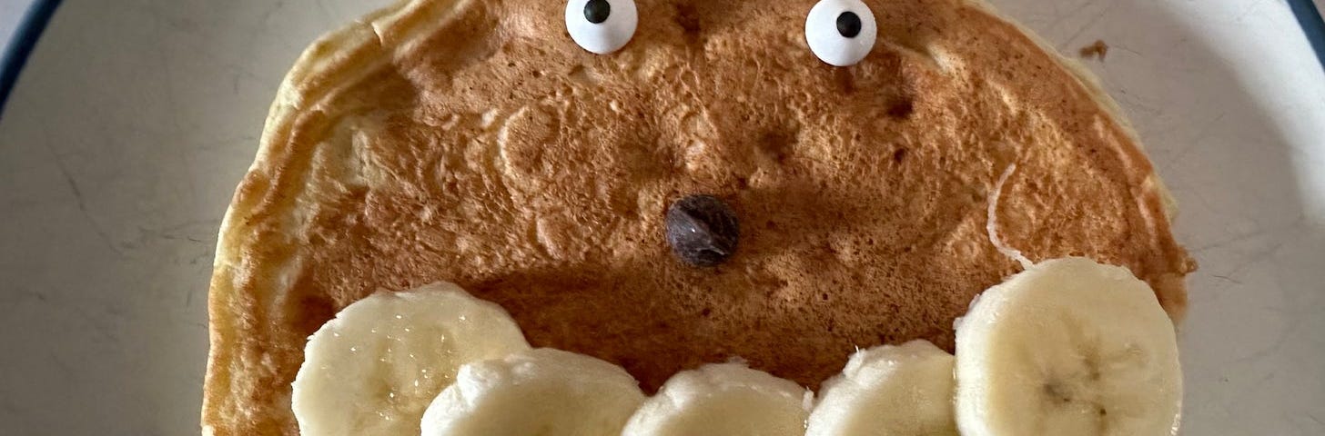 Pancake with googly eyes, a chocolate chip nose, and bananas for a smile