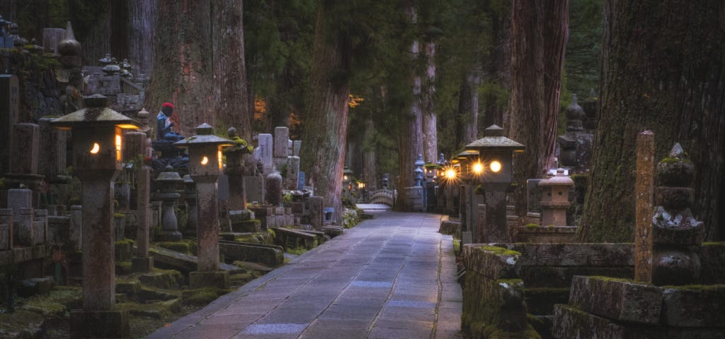 Pathway through dark Okunoin cementary, lit by stone lanterns.
