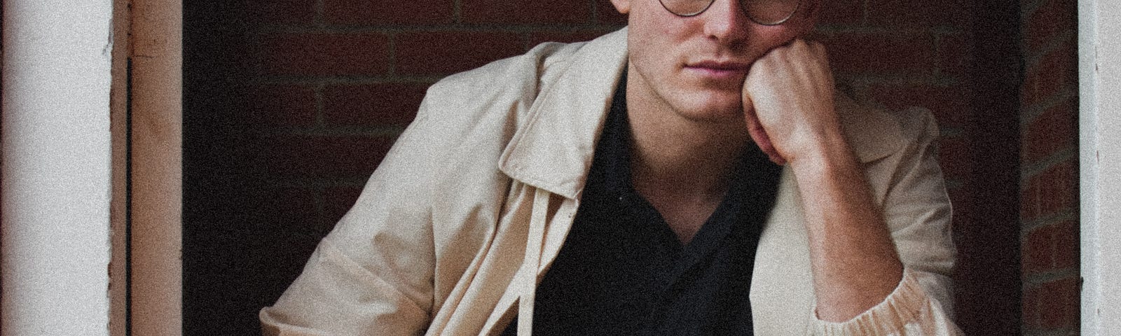 Man wearing glasses sitting with head on hand.