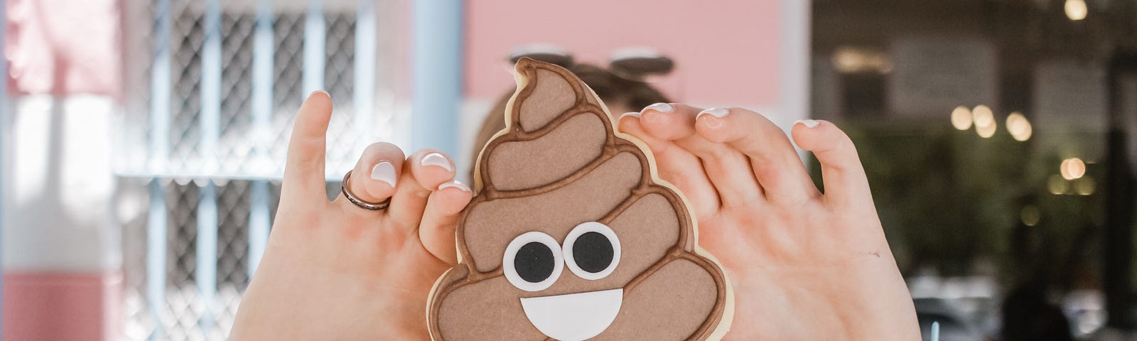 Person holding a poop-emoji cut-out to a camera.