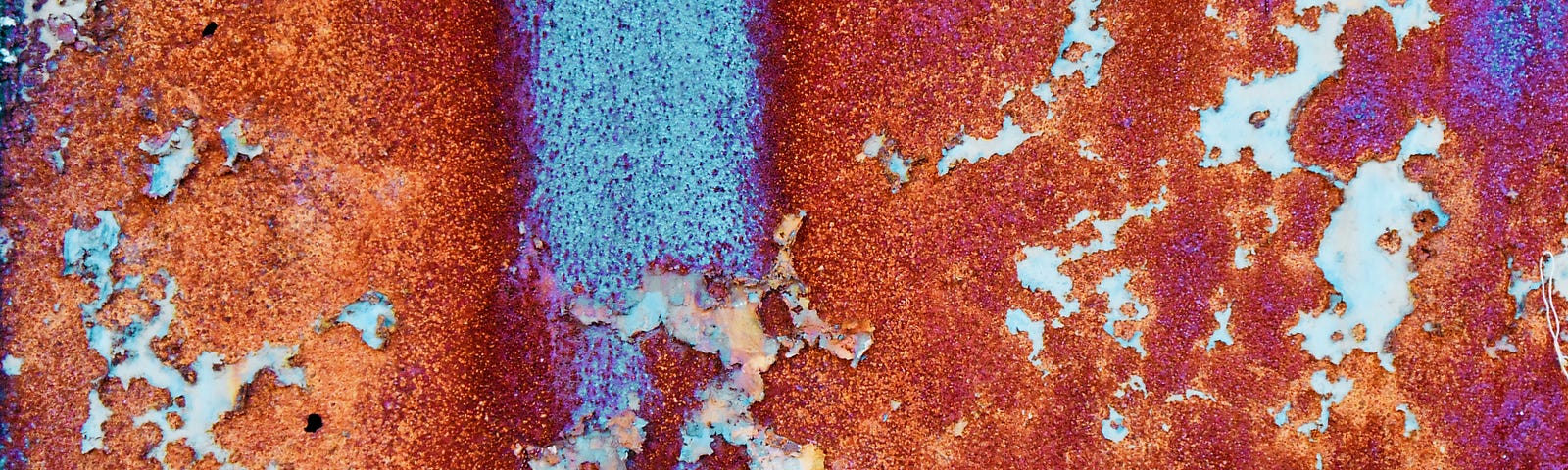 Rust on a wall, viewed in close up. Beautiful image, with a streak of vertical blue just left of midline.