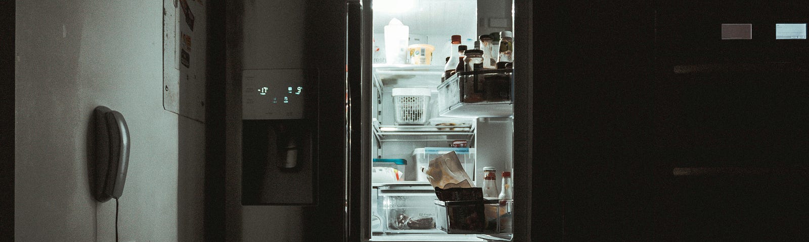 An open fridge in a dark kitchen