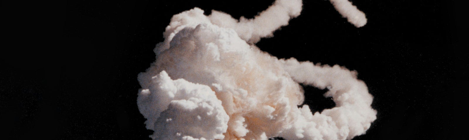 Space Shuttle Challenger explodes, leaving thick white contrails. The explosion was the first fatal disaster involving an American spacecraft in flight.
