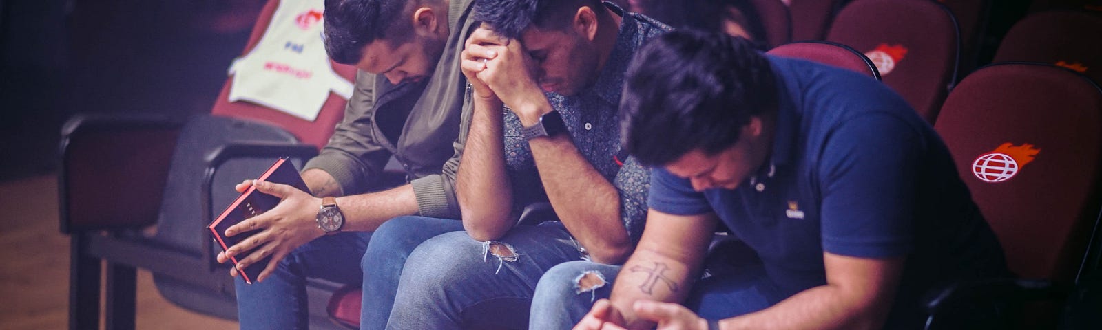three men sitting and praying