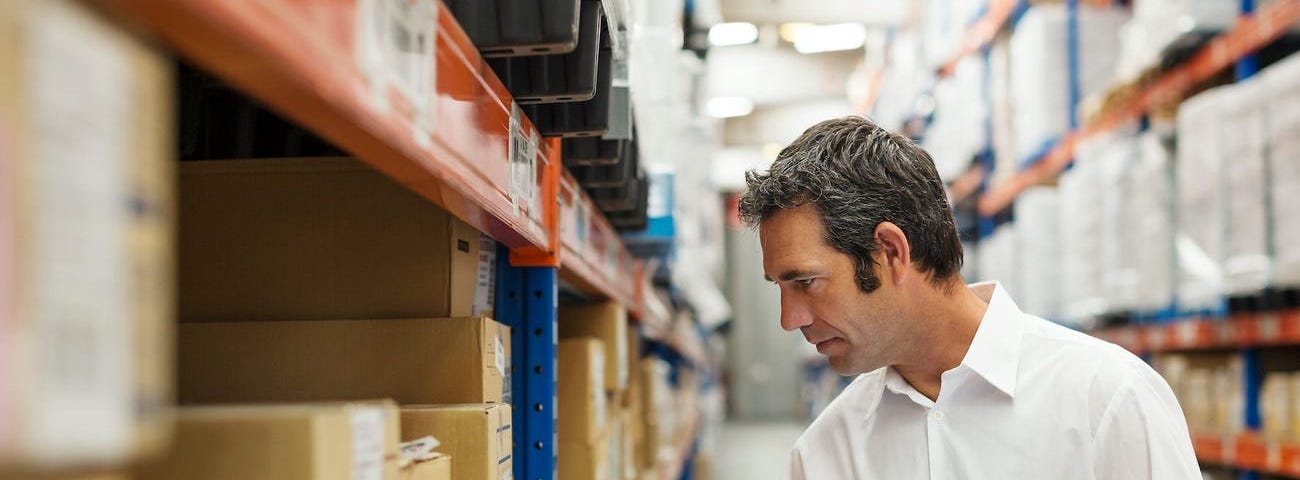 A man looking at boxes in a warehouse.