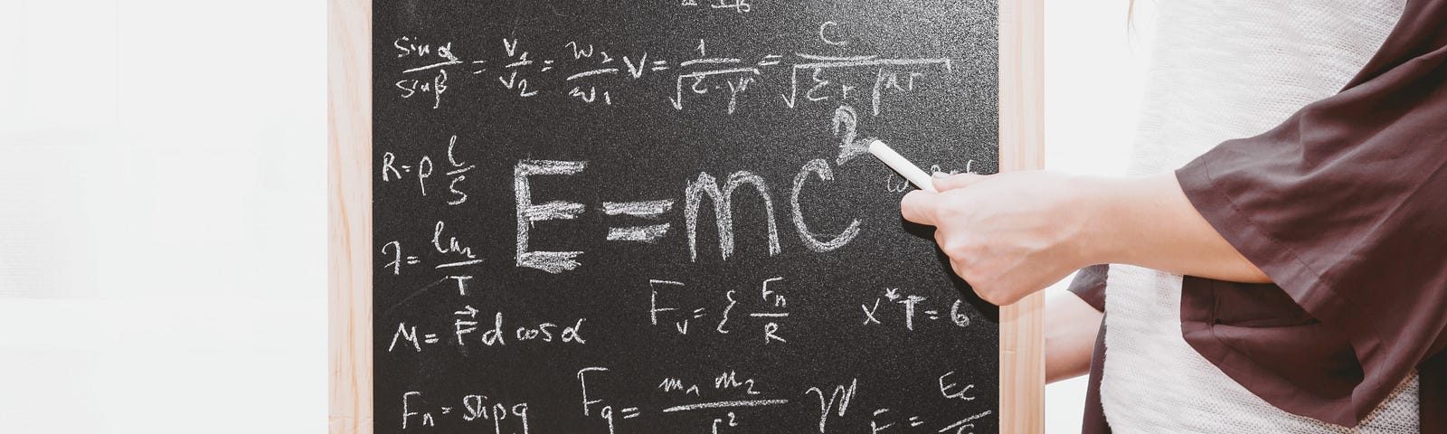 A small chalkboard showing all the physics formulas notably in largest white letters: E=mc2 as the prominent lesson.