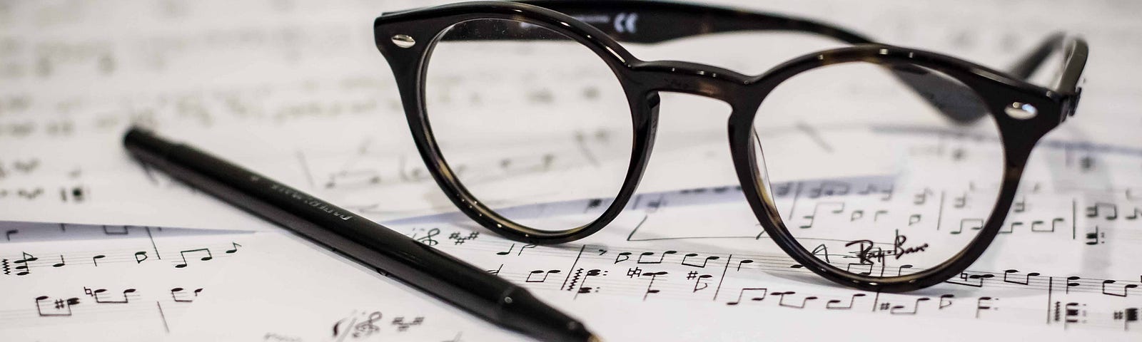Eyeglasses, a pen, and music scores