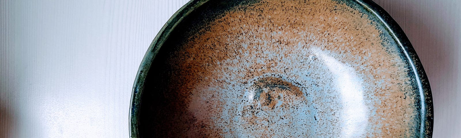 Large ceramic bowl with ombre, brown-to-gray glaze, on white tabletop.