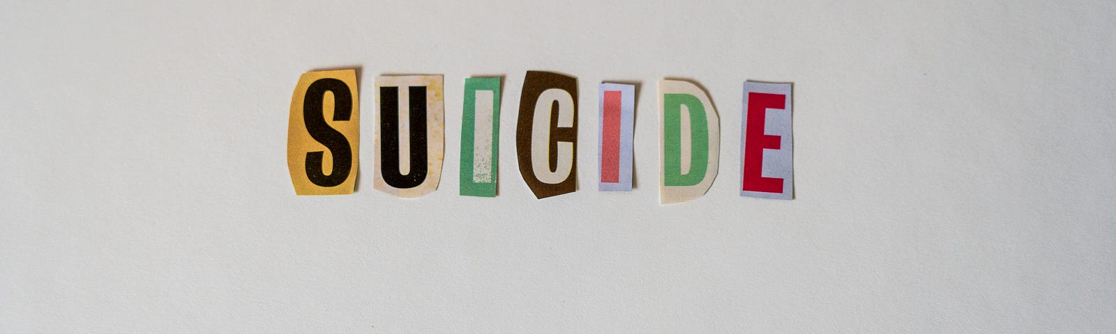 Cutting glued on a white surface to form the word SUICIDE