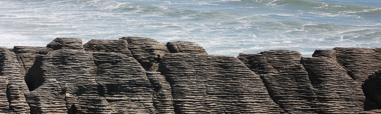 Horizontal rock layers that look like piles of pancakes along a coast line