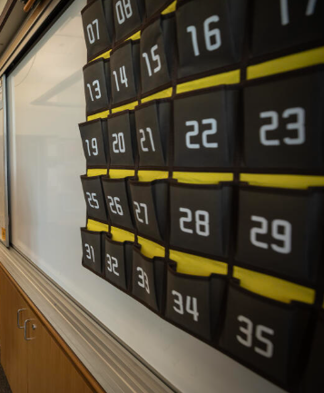 A cellphone caddy hung atop a school whiteboard.