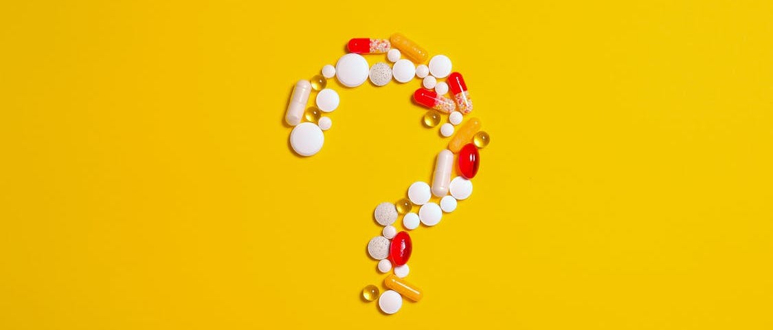 A group of pills and capsules formed into a question mark.