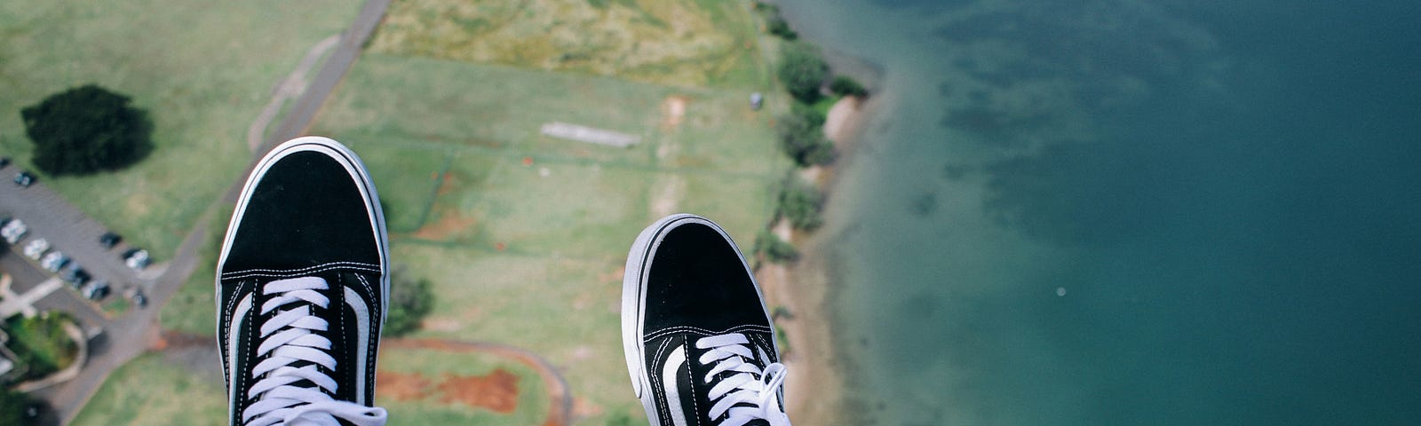 Photo by Colton Jones on Unsplash — an aerial view of a shoreline but with two legs dangling in the scene as if the person were floating above the world.