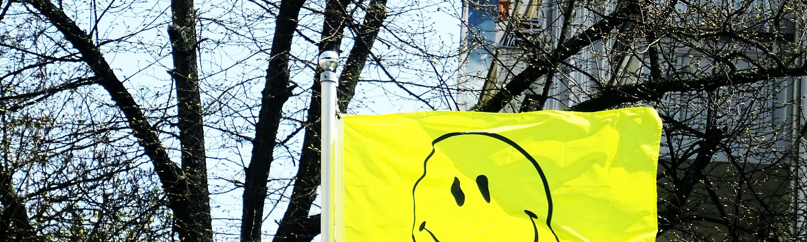 A smiley face flag flies in a city street