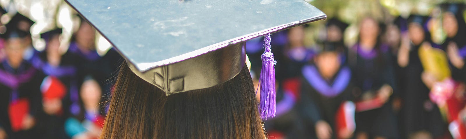 This shows a girl wearing a graduation cap facing a crowd.