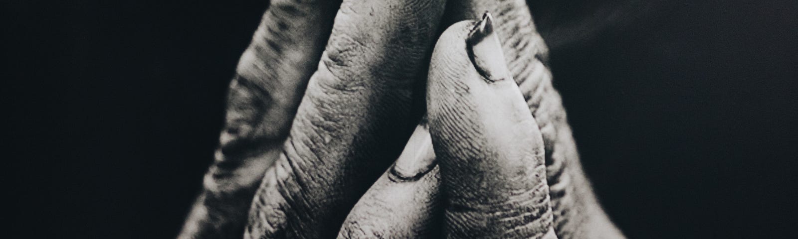 black and white image of weathered hands praying to God for guidance