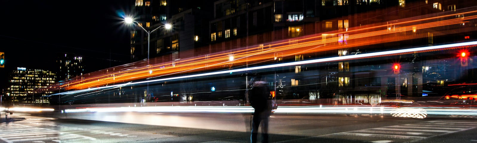 Man standing on curb as traffic whizzes by.