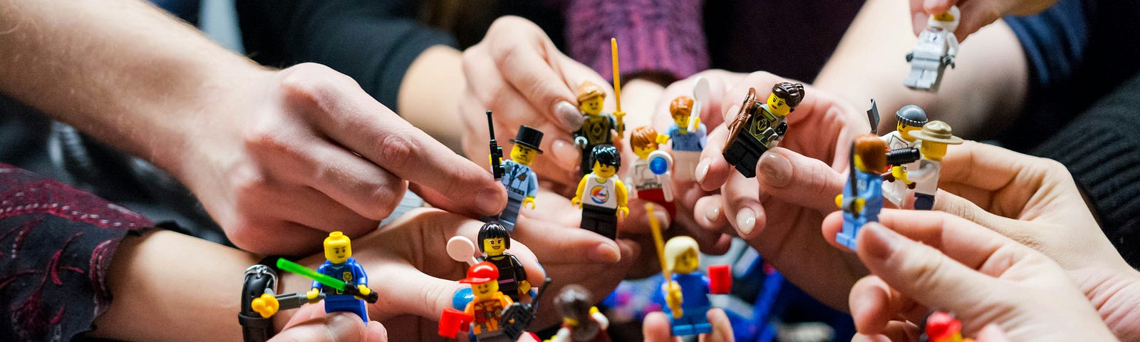 A team is all in with hands in a group holding toy figurines.