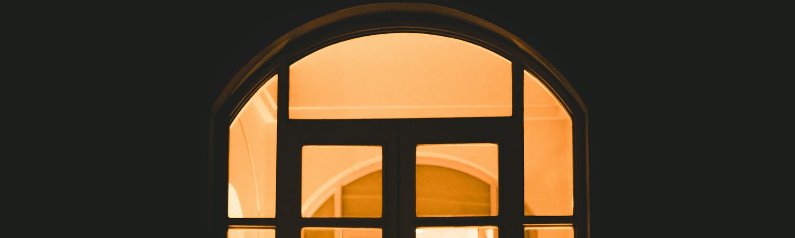 A cat silhouetted in an arched window