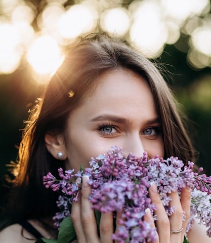 Beautiful green eyed young woman holding flowers to her face