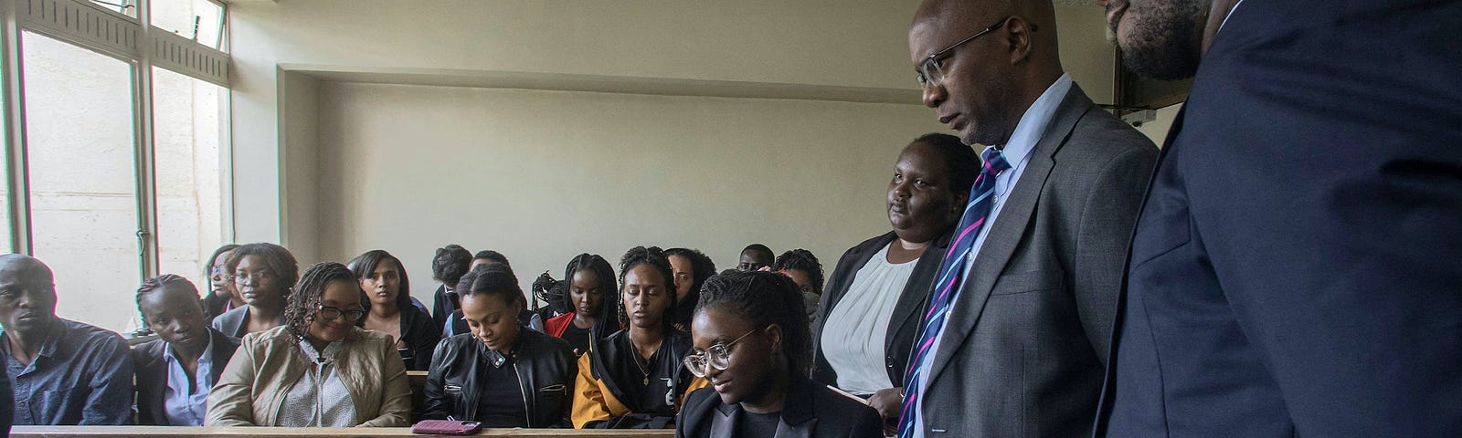 Kenyan lawyers stand around a computer for a virtual meeting.