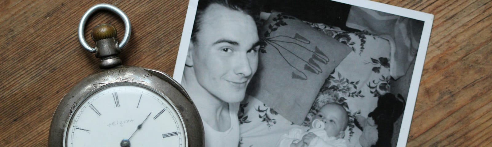Old black and white photo of father and baby. Stop watch beside the photo.