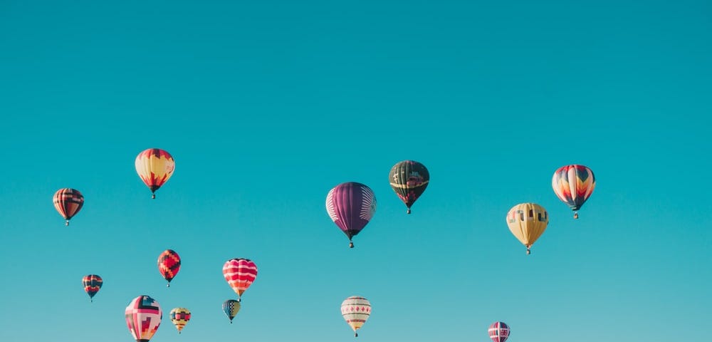 Many, many hot air balloons against a blue, blue sky.