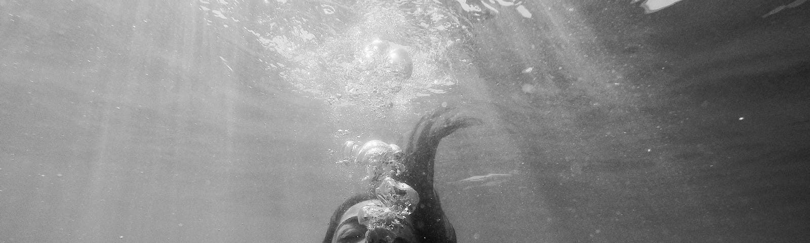 A young woman slips underwater for a moment while swimming at night