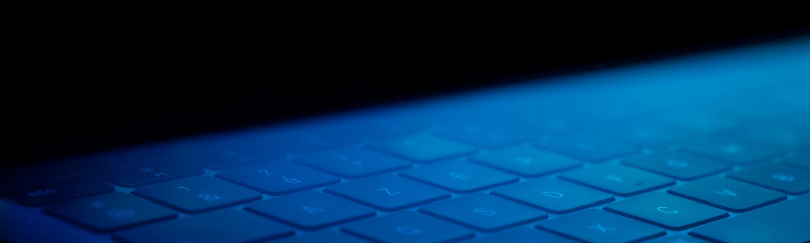 Computer keyboard faintly lit by blue light