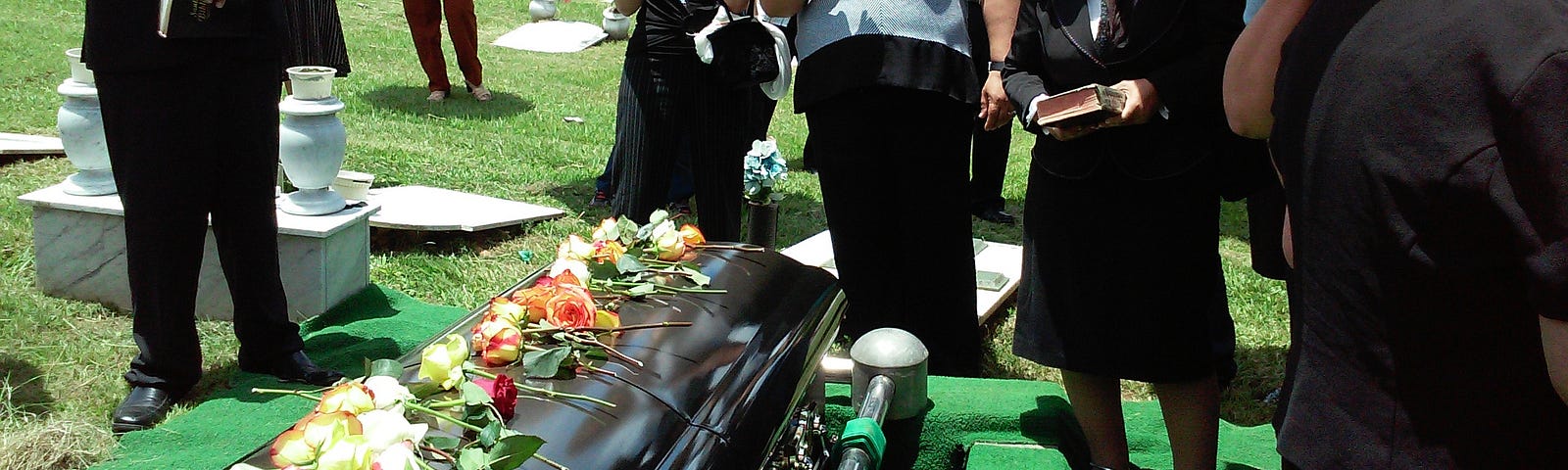People standing in front of a casket with flowers on it