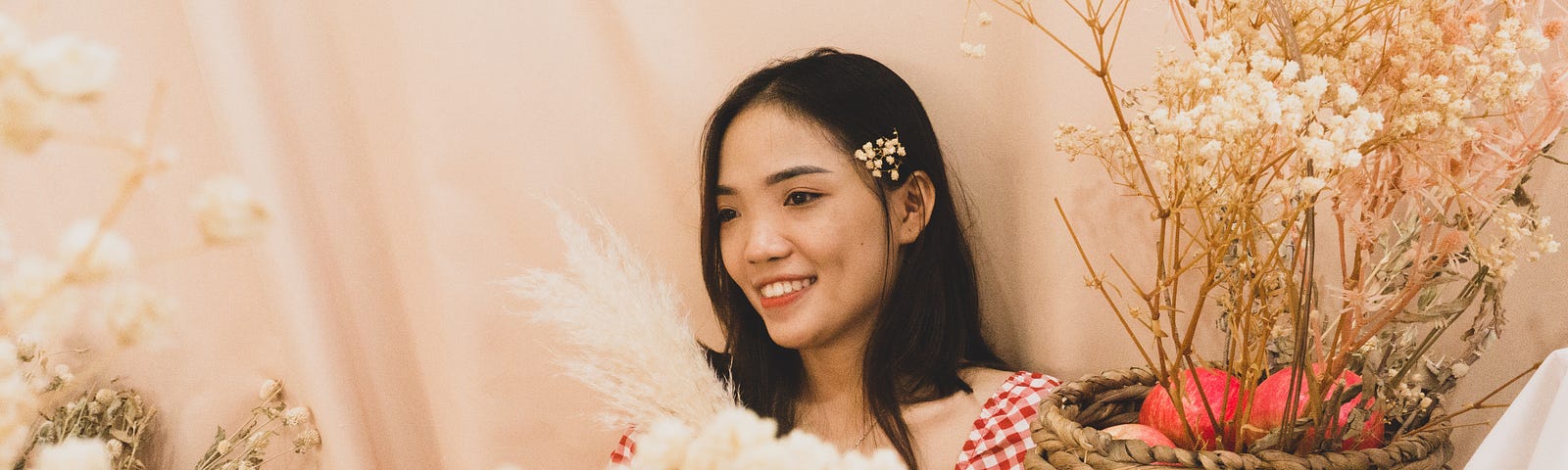 A photo of a happy young woman with a woven vase of flowers