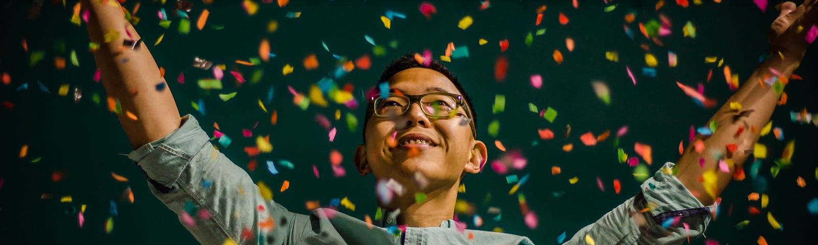 Man looking happy and celebrating with confetti falling around him.
