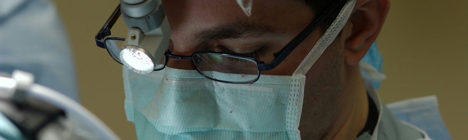 surgeon’s face wearing mask looking down onto patient