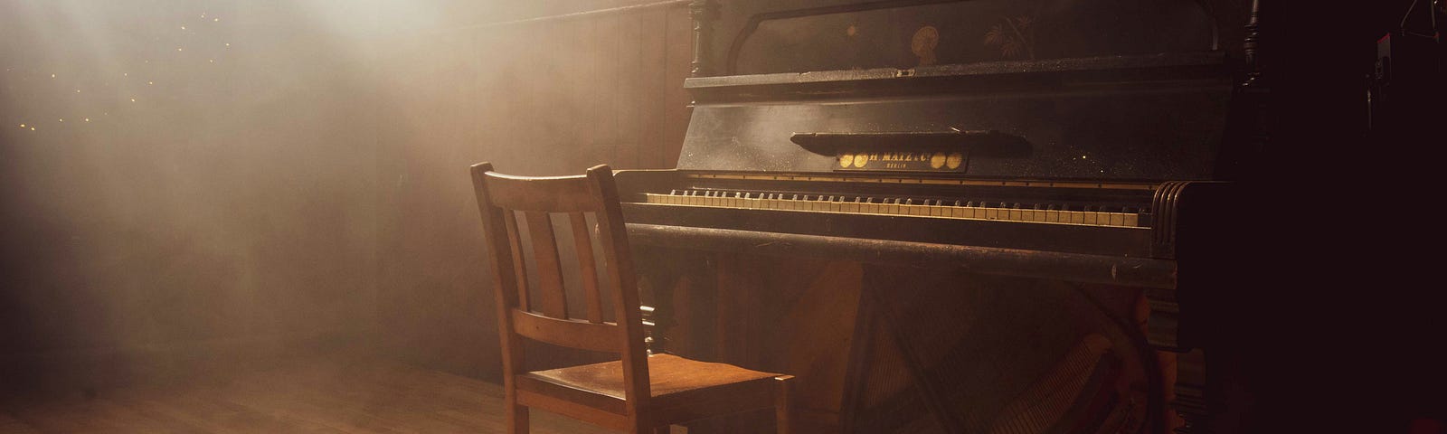 Sitting chair in a dusty room facing an old piano — Photo by Paul Arky on Unsplash