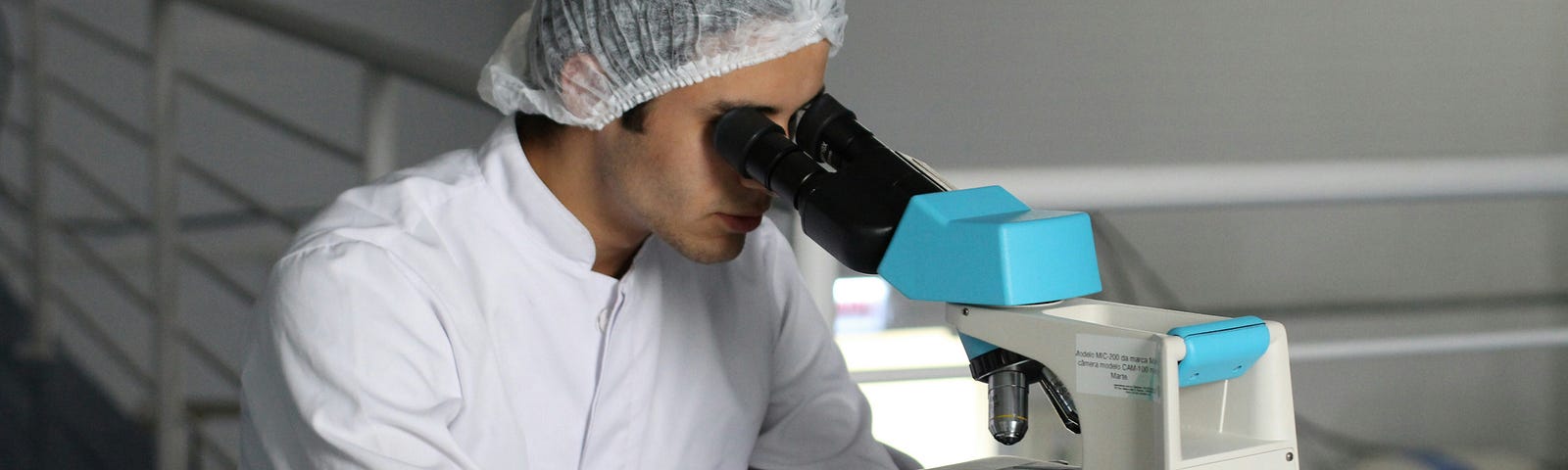 Scientist looking into microscope wearing lab coat